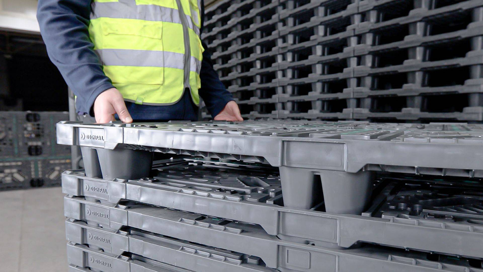 A warehouse employee holding a grey Digipal plastic pallet. 